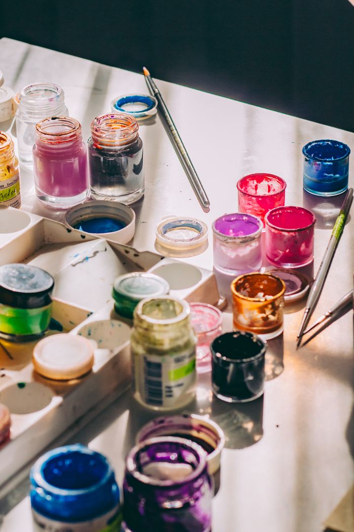 A vibrant array of acrylic paint jars and brushes on a sunlit table, perfect for creative projects.