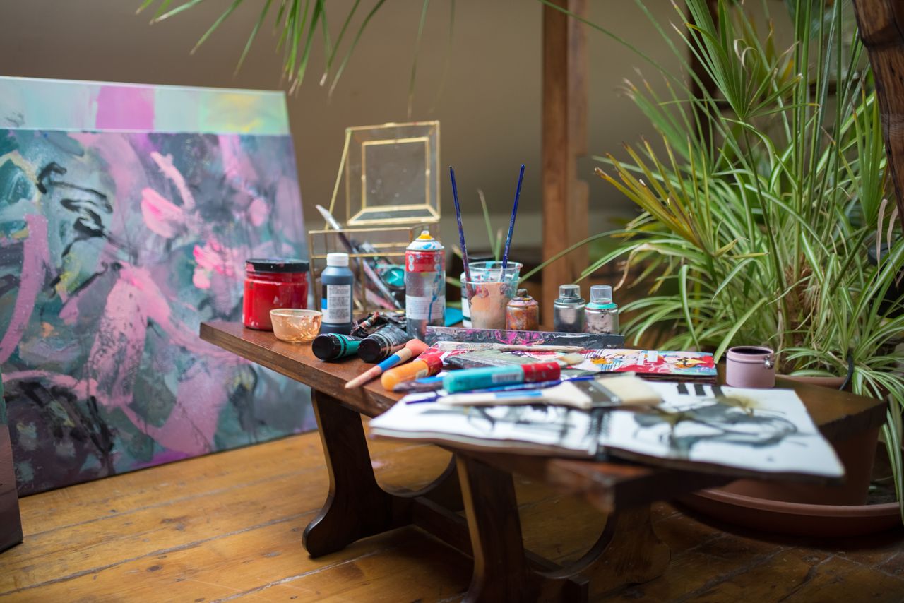 A vivid art studio setting showcasing diverse painting supplies and a colorful canvas.